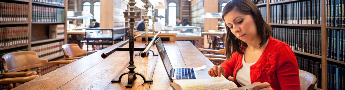 woman in a red shirt reading in a law library