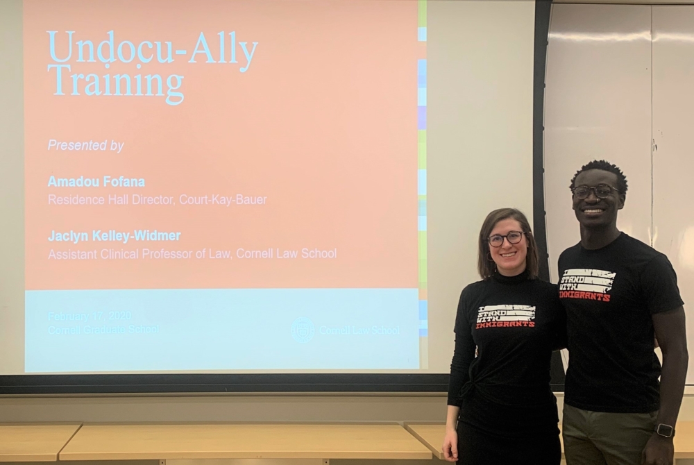 a man and a woman stand in front of a PowerPoint screen that reads “Undocu-Ally Training.”