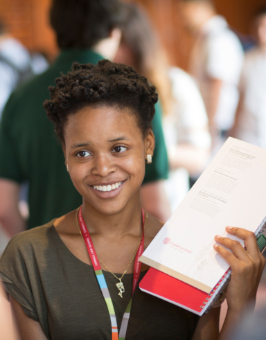 young woman with a striped lanyard talking to someone in the foreground