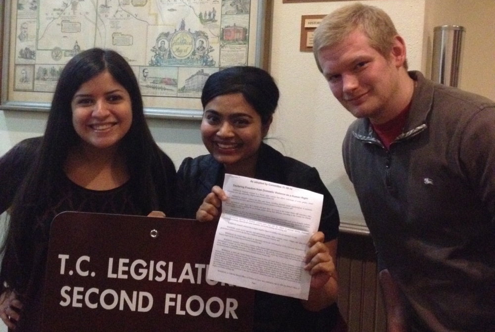 three students with a sign saying TC legislator second floor