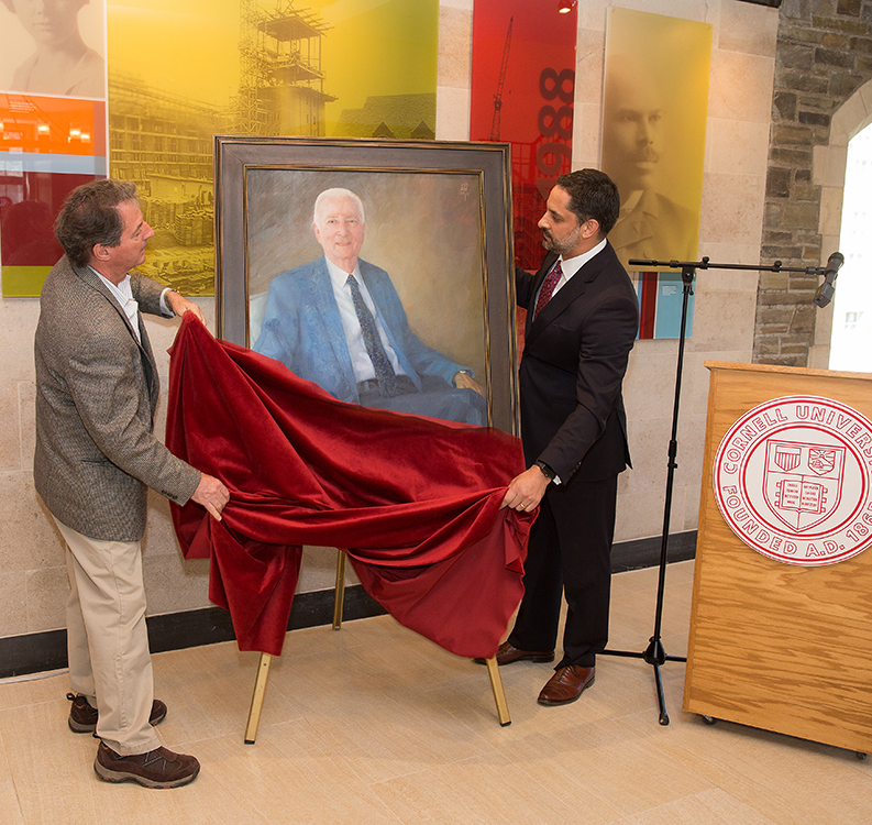 two men remove the cover from a wall painting