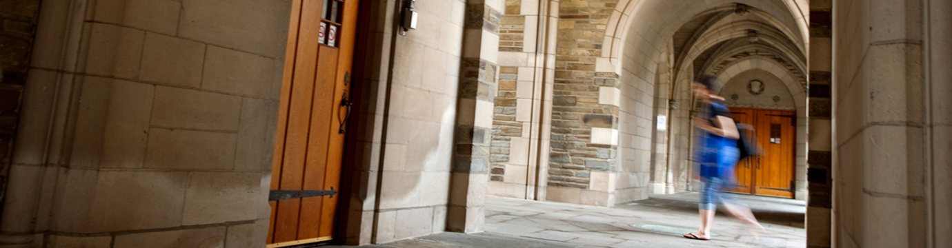 A student is walking under arches outside the law school