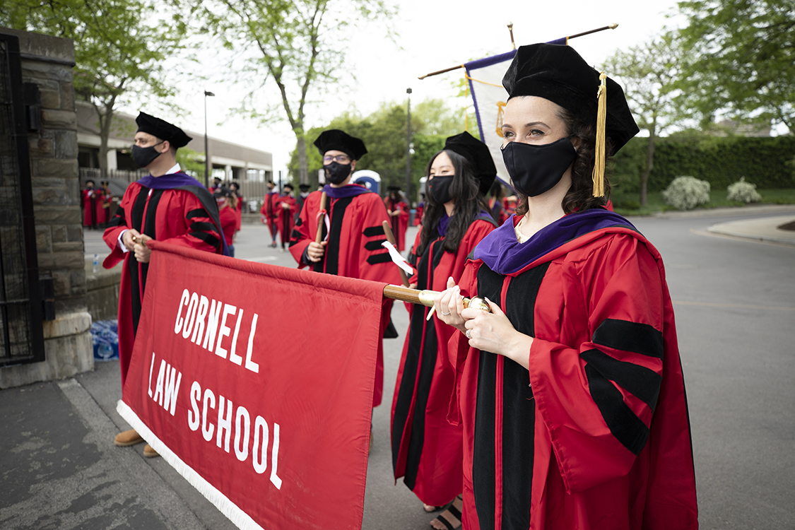 Students in convocation regalia holding Cornell Law School banner
