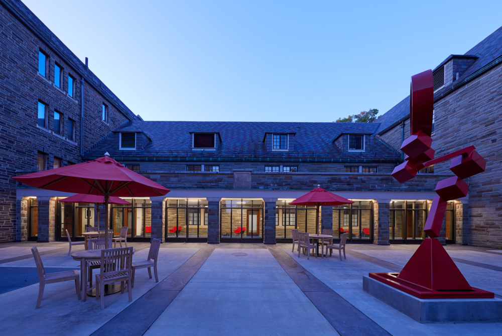 umbrellas, tables, and red statues in a courtyard of a brick building