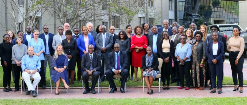 Photo of several people standing for a group shot outside of a large grey building