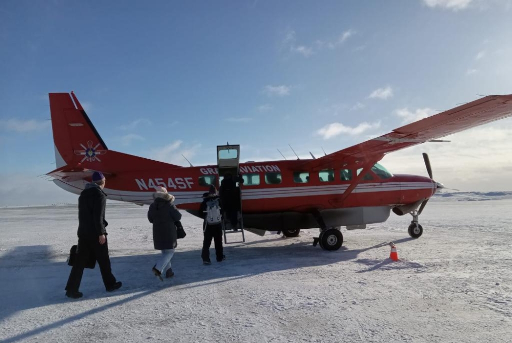 people boarding a small plane on a snow covered field