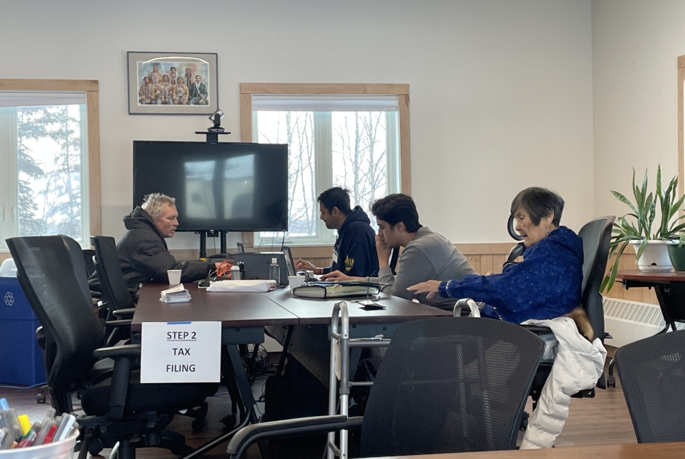 people around a table with computers and paperwork