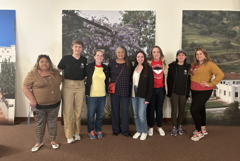 group of people in front of a large photo of a crop