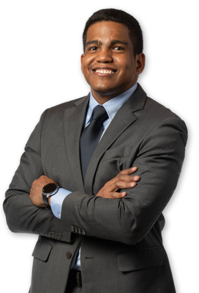 A silo'd photo of a man wearing a grey suit and crossing his arms. He has a white background behind him.