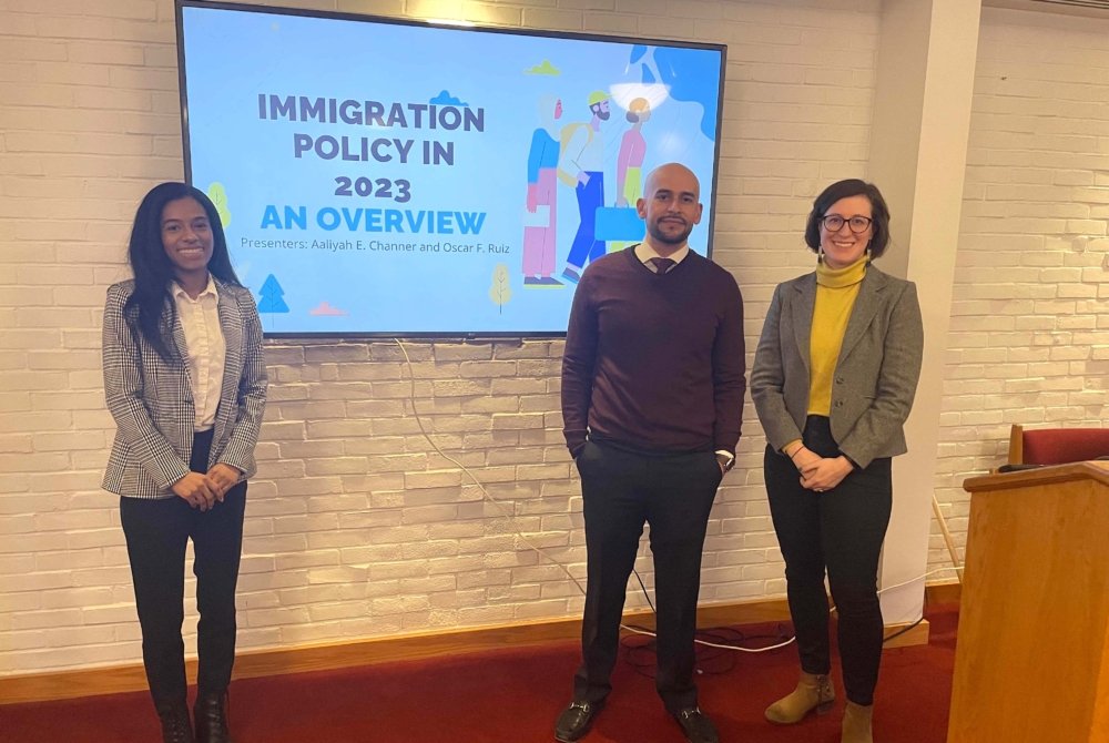 Students and faculty in front of a screen that says Immigration policy in 2023 an overview.