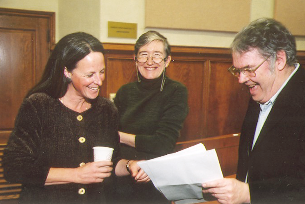 Photo of three people smiling and looking down at paperwork in the gentleman's hand who is on the far right.