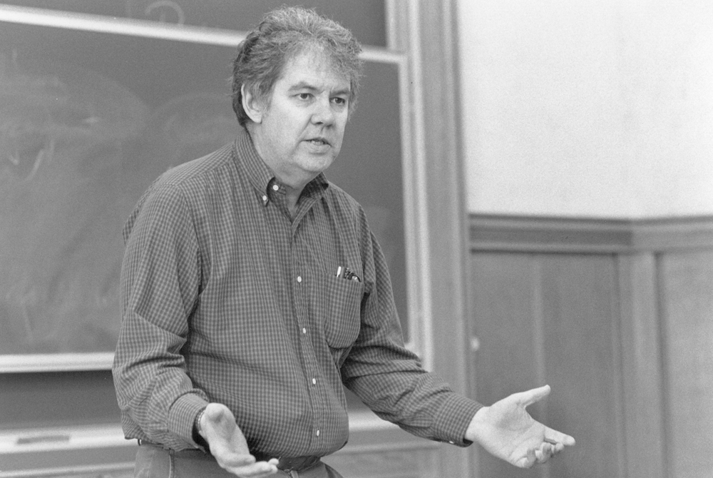 Photo of Steve Shiffrin lecturing in front of a classroom. The photo is black and white and his hands are outstretched in conversation with his palms facing upwards.