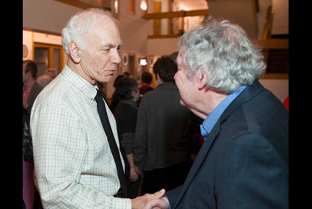Photo of two men wearing business attire facing each other in conversation at an event.
