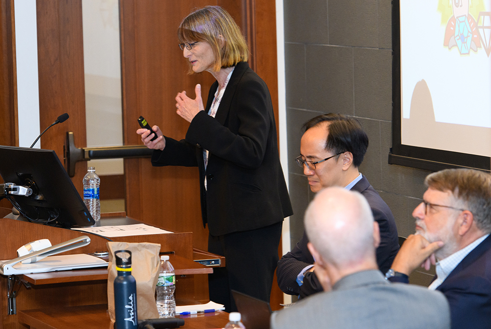 A female panelist speaking with panelists including Professor Chang seated in the foreground.