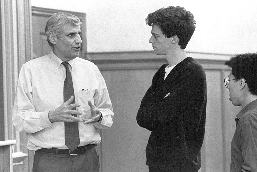 photo of Rossi talking to a student in a black sweater in a classroom