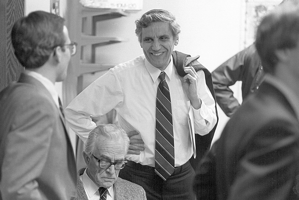 photo of Rossi talking to a man in glasses- Rossi has his jacket slung over his shoulder