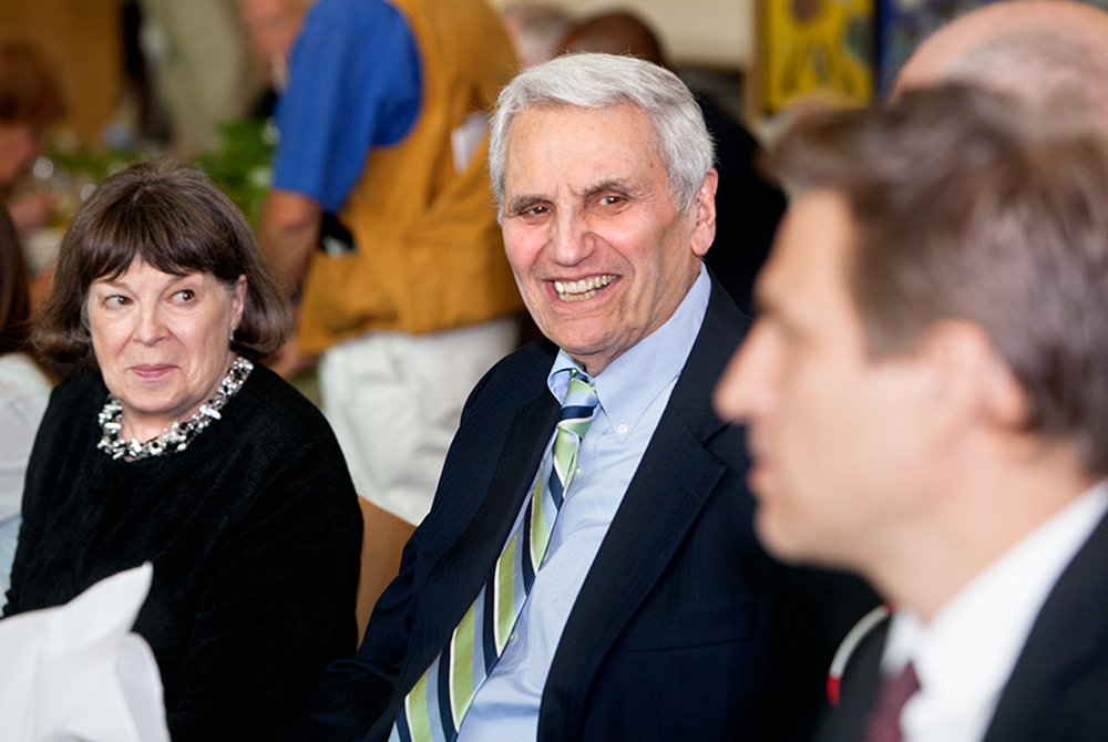 photo of Rossi sitting next to a woman and a man at an event, talking