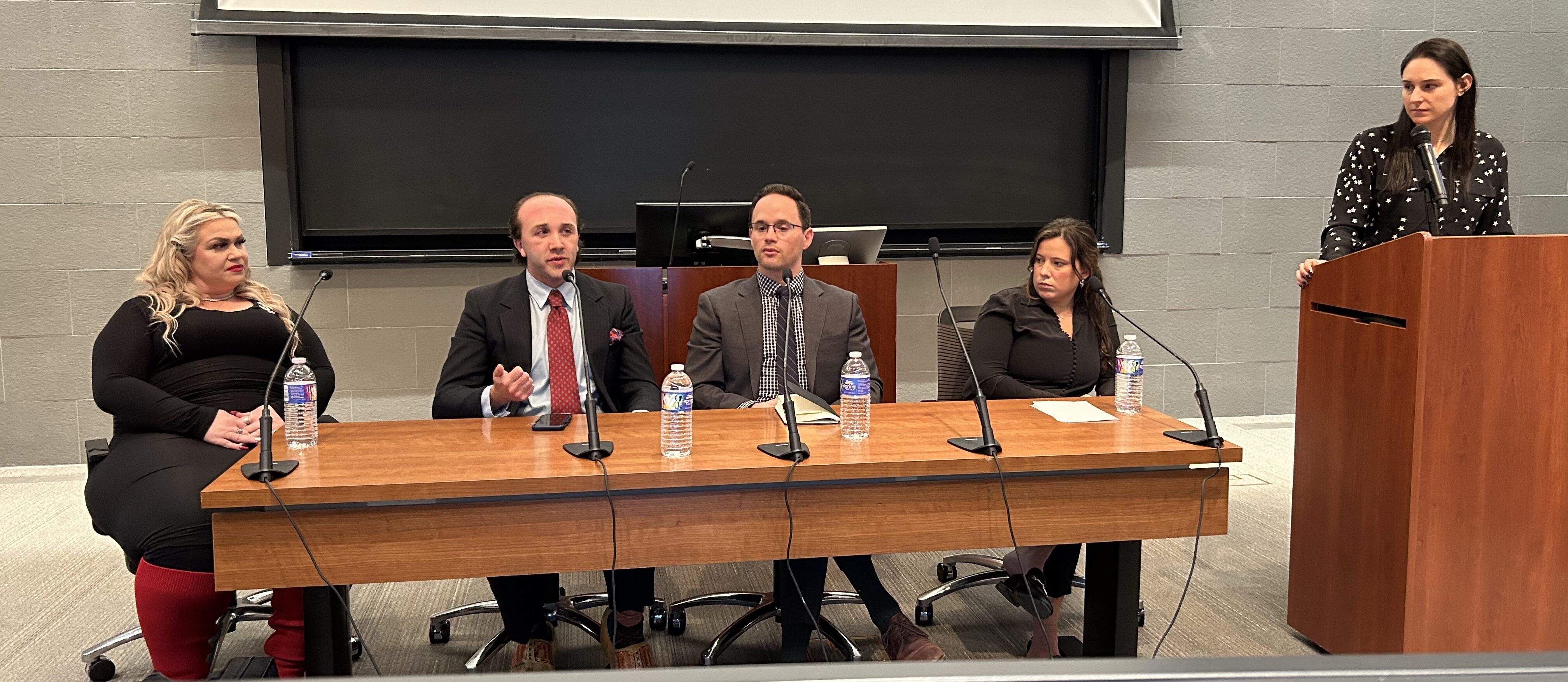 Panelists from a military sexual assault panel from March 2024- screen in background with powerpoint on it