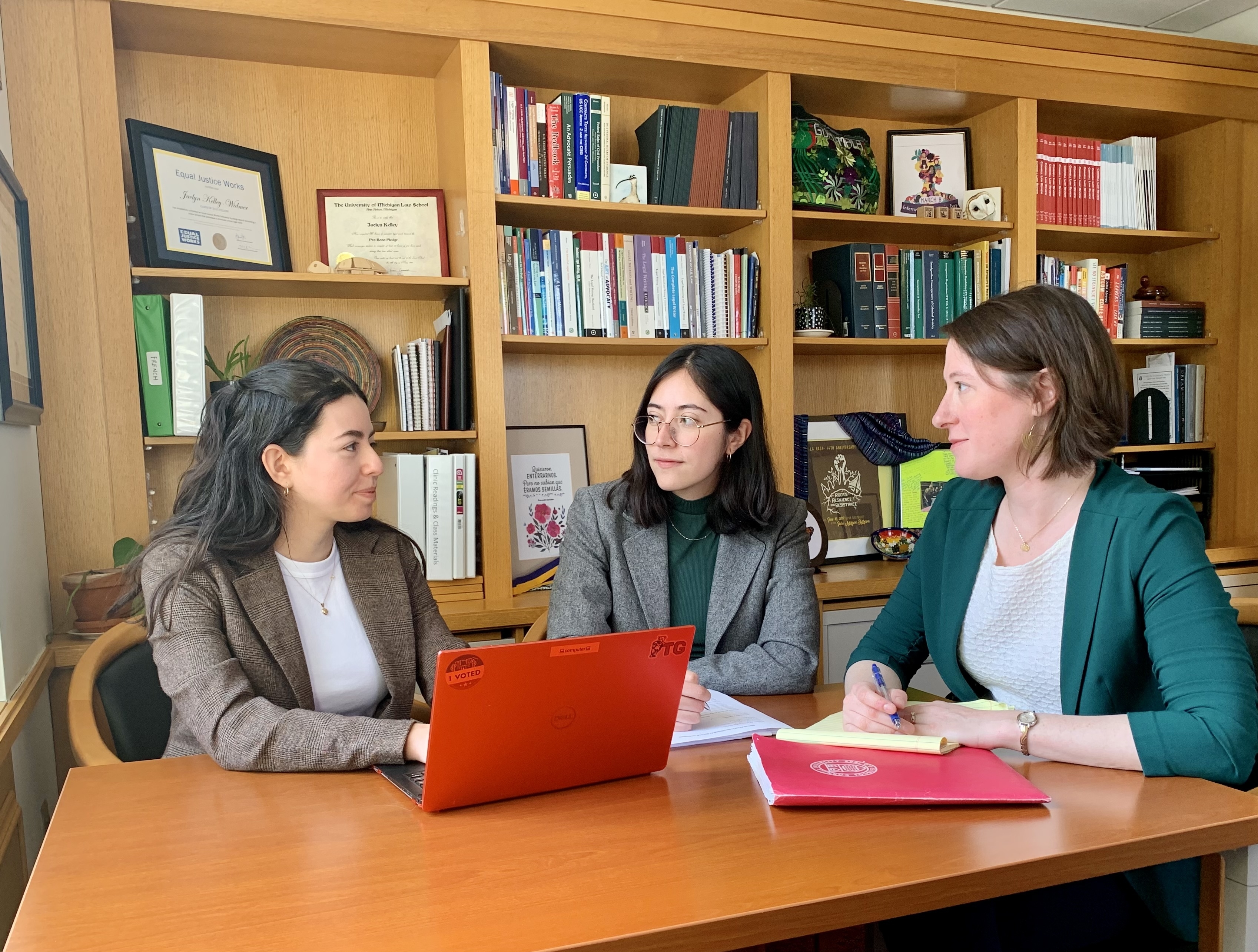 two students and a faculty member talking in an office