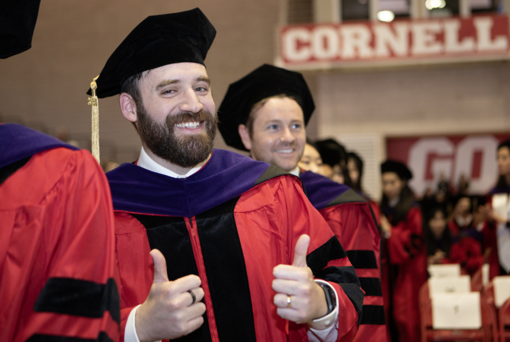a student posing with his thumbs up in his regalia