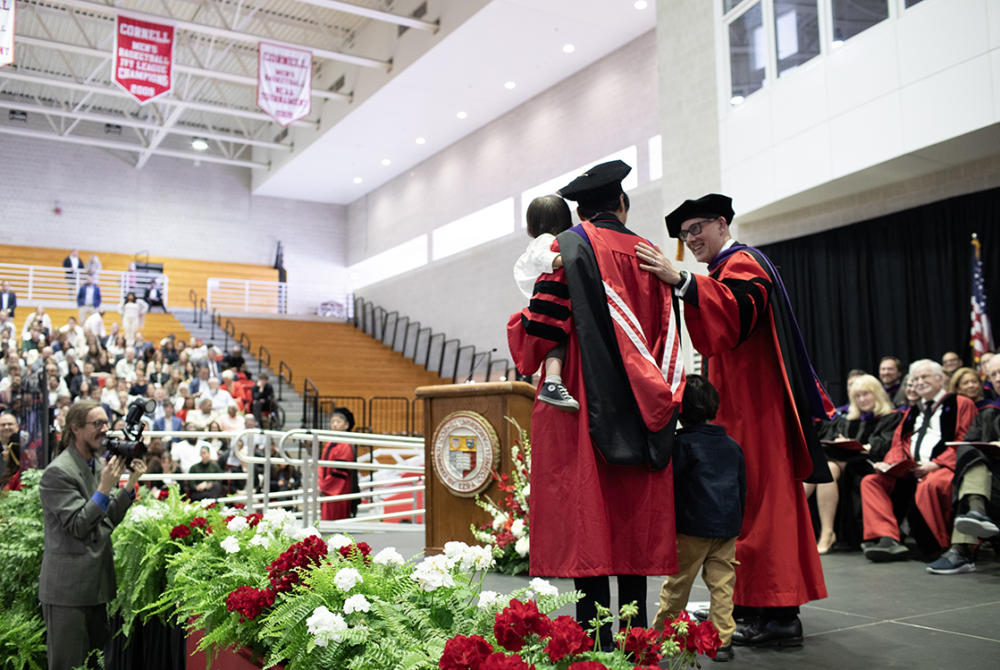 Dean Ohlin and a father and his two kids posing on stage for a photo at graduation