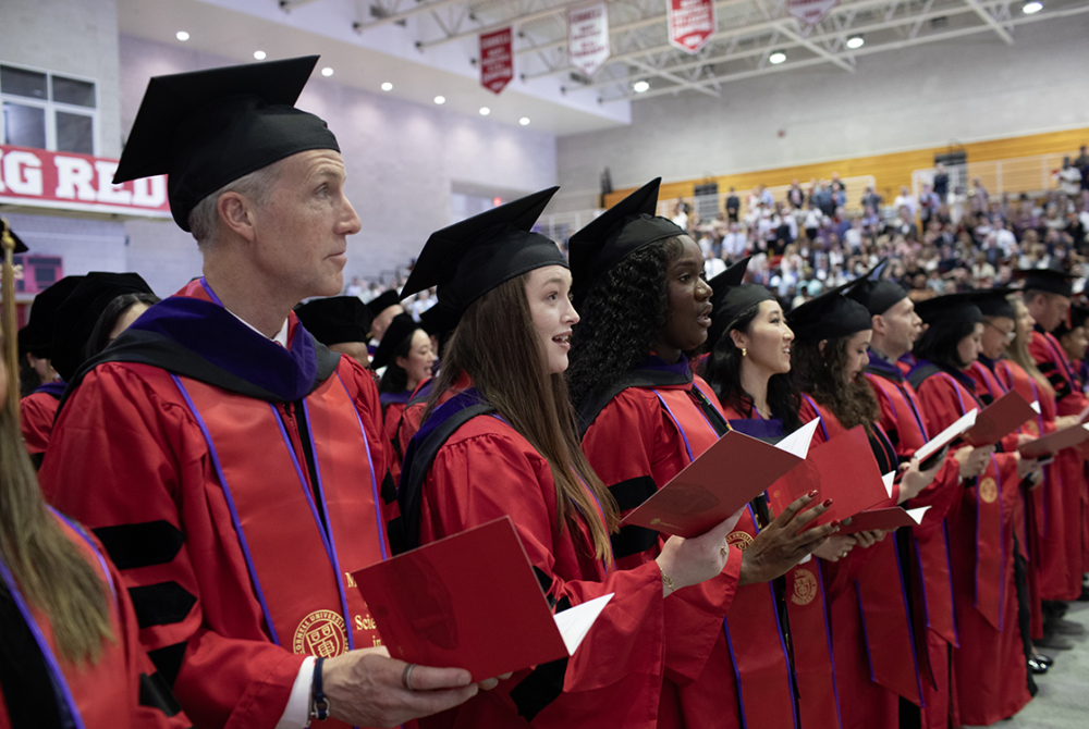 MSLS students standing in a row reading from their convocation booklets