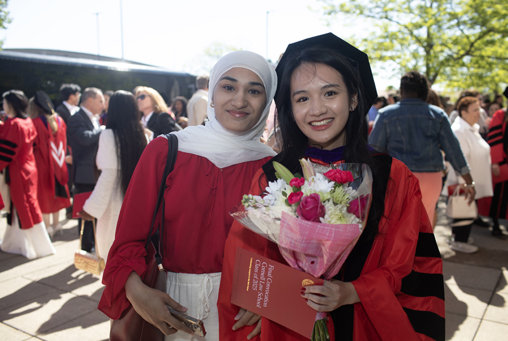 a graduate holding flowers poses with a family member
