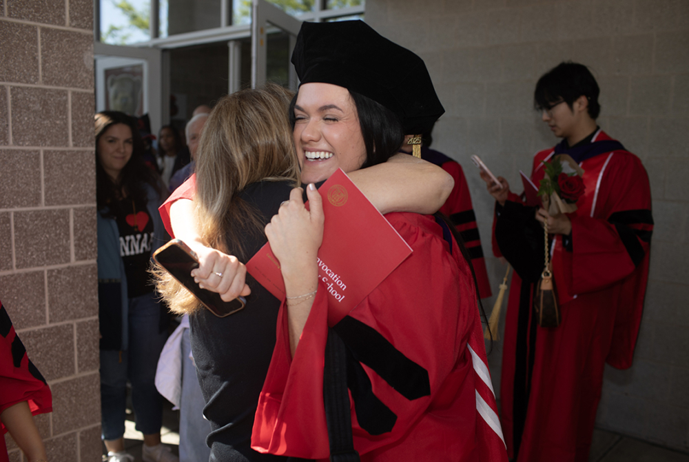 two students hugging after graduation