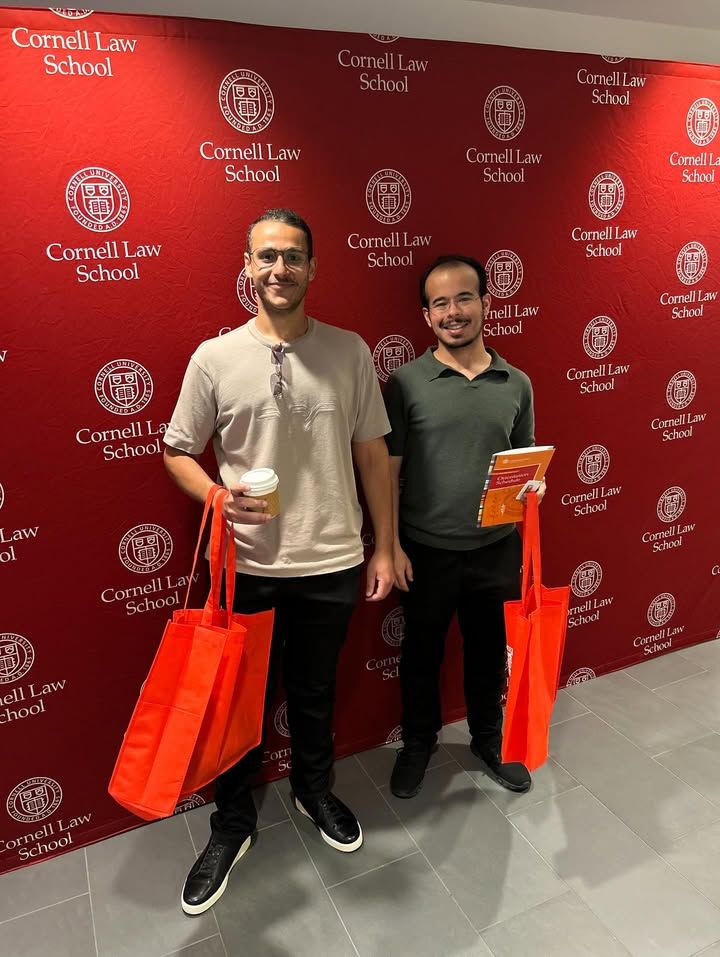 2 llm students posing for photo in front of backdrop