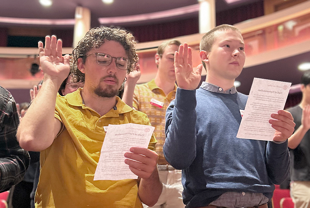 two students reciting oath of professionalism with their hands up