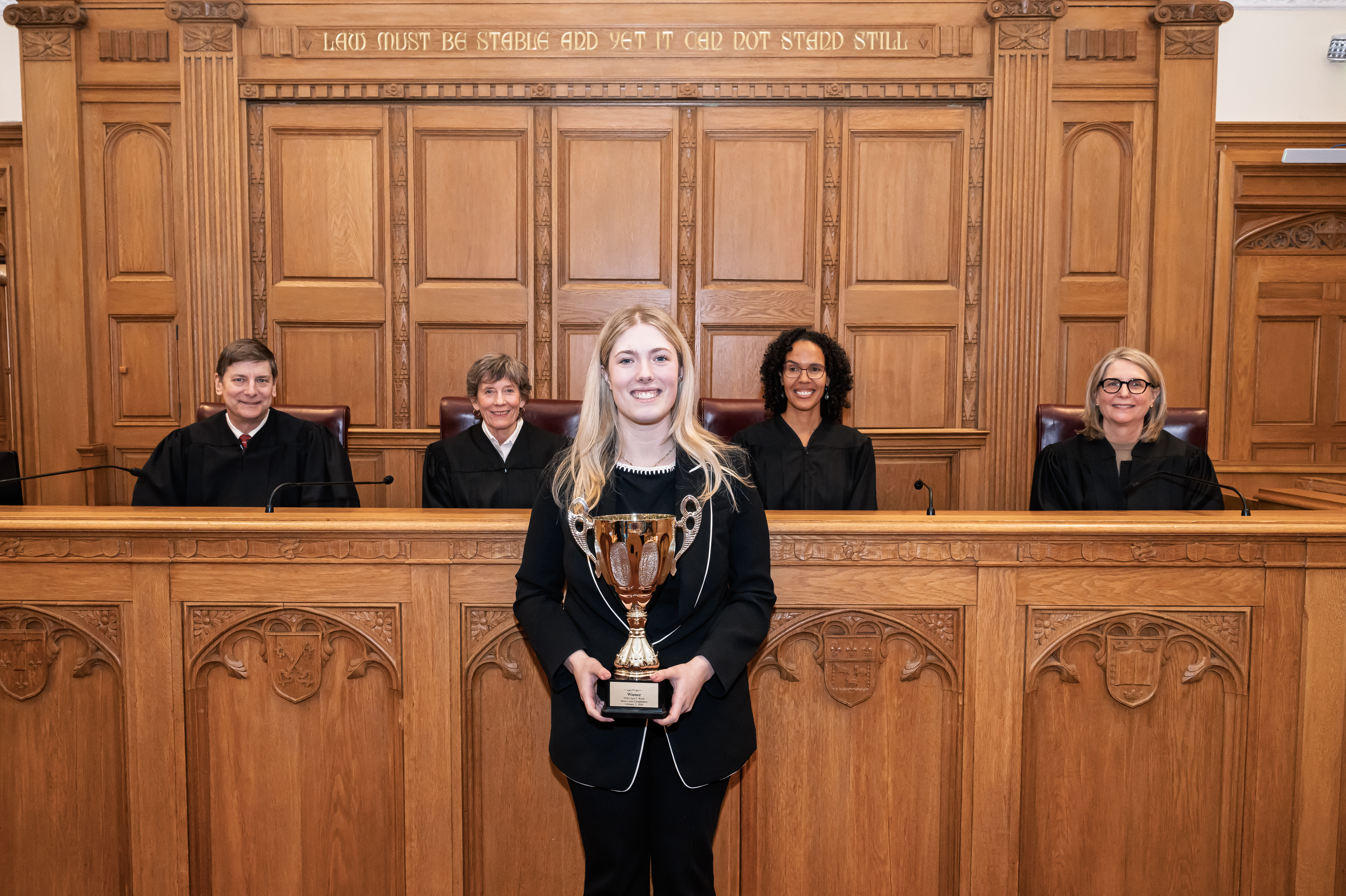 pictured is 2026 rossi moot court competition winner Paxton Trevett with trophy and behind her is judges