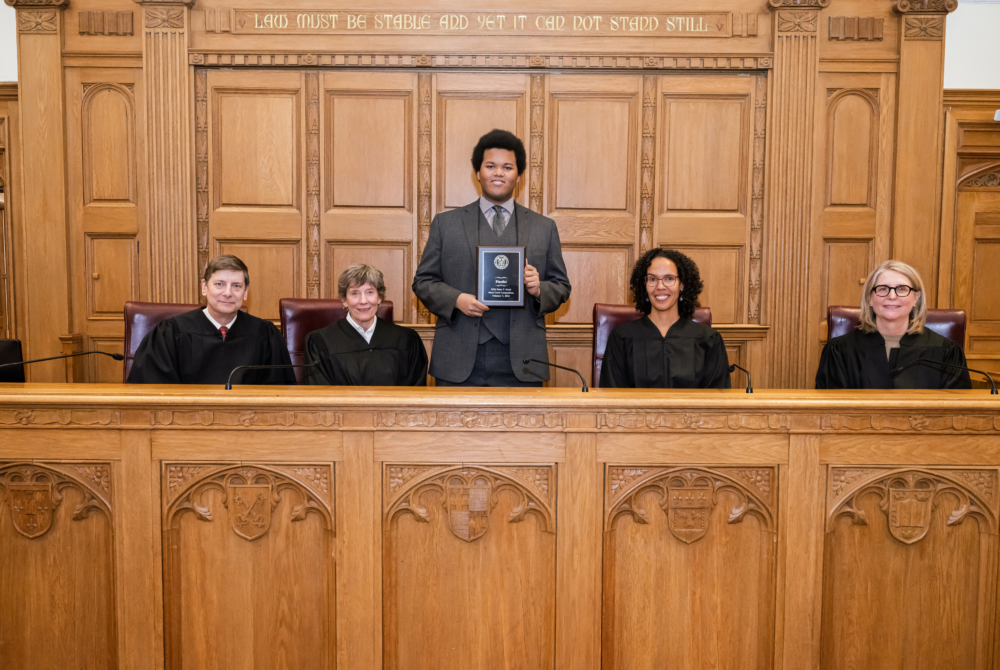 pictured is 2026 rossi moot court competition runner up Giovan Soares with trophy and behind him is the judges