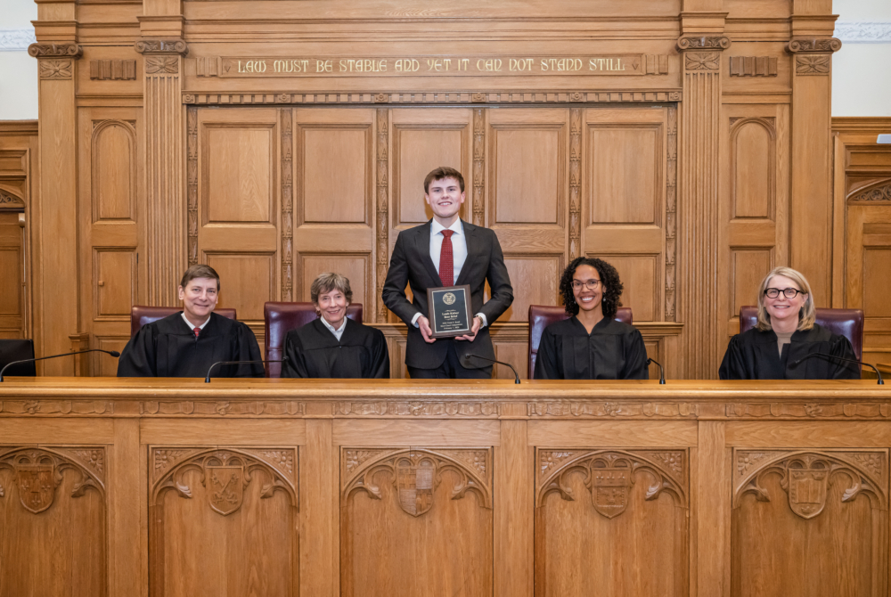 winner of the Louis Kaiser Best Brief Competition was Elliot King ’27 posing with judges next to him at 2026 rossi moot court competition