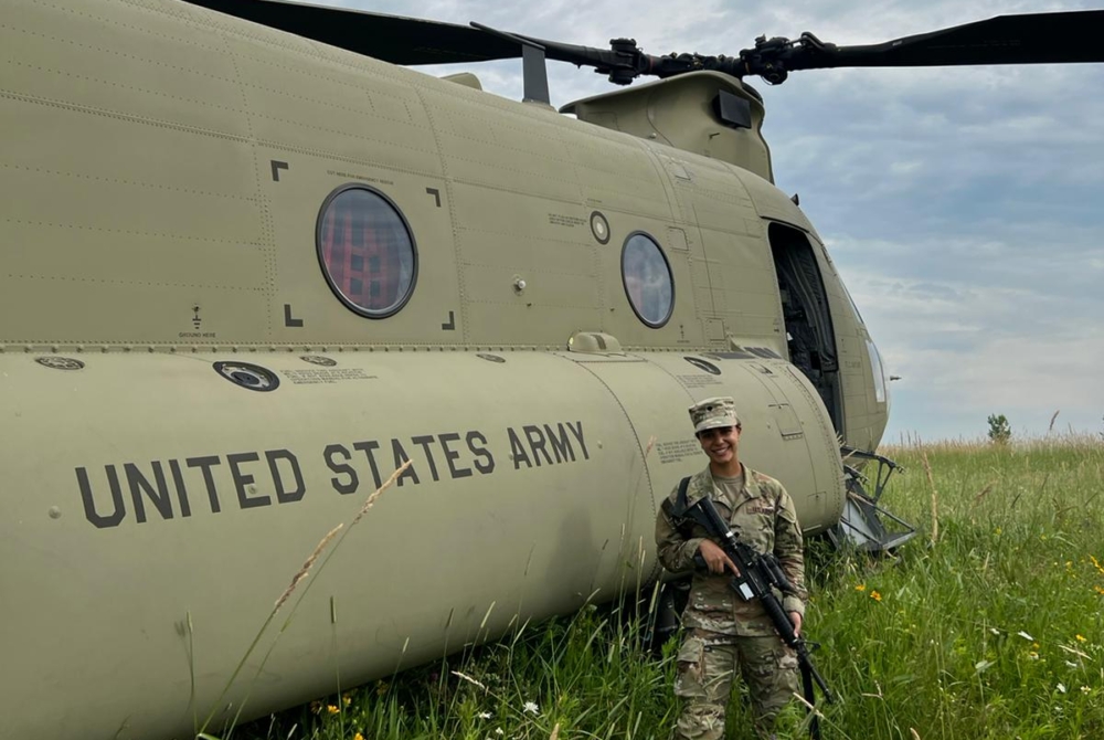 Estefania Solis '27 posing by helicopter in National Guard uniform