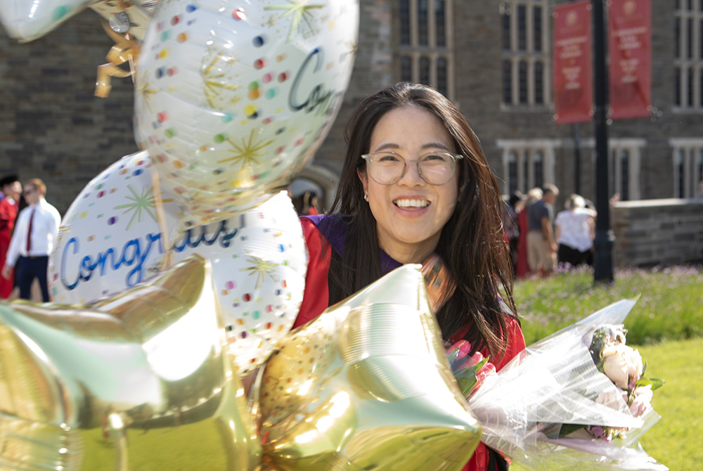 Graduate outside with balloons.