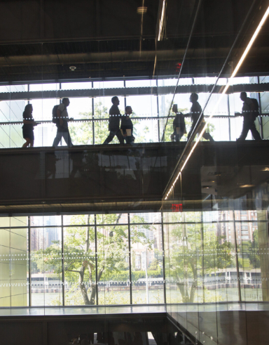 people walking on a glass bridge inside a building